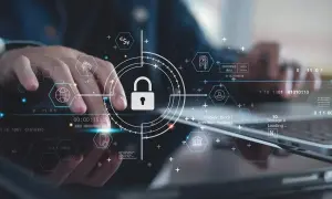 Ręce pracujące nad technologią, symbol kłódki i ikony sieciowe podkreślają znaczenie cyber security.