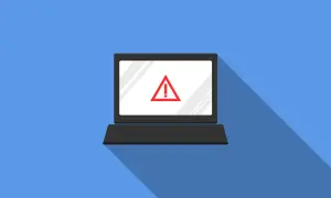 Laptop z czerwonym znakiem ostrzegawczym na ekranie. Symbolizuje zagrożenie w cyberbezpieczeństwie.