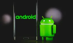 Zielony robot Android obok telefonu z napisem "android 13" na ekranie.