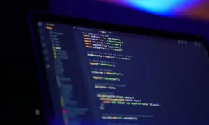 Kod JavaScript na ekranie laptopa, widać fragmenty kodu, importy i komentarze. Oop!