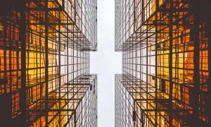 Szklane wieżowce odbijające pomarańczowe światło, tworzące geometryczny wzór. Czysta architektura w nowoczesnym wydaniu.