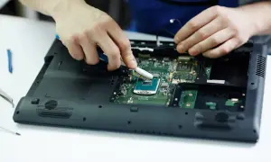 Ręce czyszczą procesor laptopa szczoteczką. Może to pomoże, gdy laptop nie chce się włączyć.