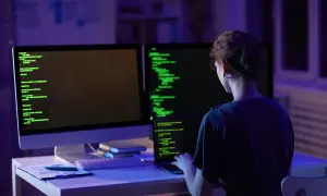 Kobieta programistka pracuje nocą nad kodem. Na ekranach widać zielony tekst, a w pomieszczeniu panuje niebiesko-fioletowe oświetlenie. To jej codzienny crud.