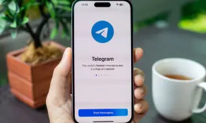 Dłoń trzyma smartfon z ekranem startowym aplikacji Telegram. To szybka, darmowa i bezpieczna aplikacja do wysyłania wiadomości.