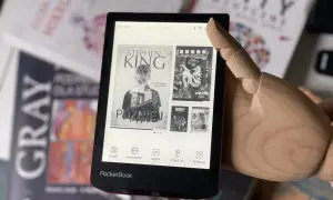 Drewniana dłoń wskazuje na ekran czytnika pdf z okładkami książek Stephena Kinga i "Ghost in the Shell".