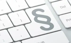 Klawisz z symbolem paragrafu na białej klawiaturze. Idealny do pisania tekstów prawnych lub tworzenia nowych akapitów.