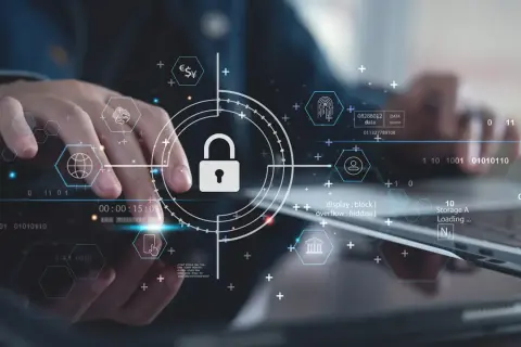 Ręce pracujące nad technologią, symbol kłódki i ikony sieciowe podkreślają znaczenie cyber security.