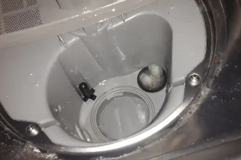 Wnętrze zmywarki Beko z widocznym czarnym elementem i zatkanym filtrem, prawdopodobnie przyczyna błędu E01.