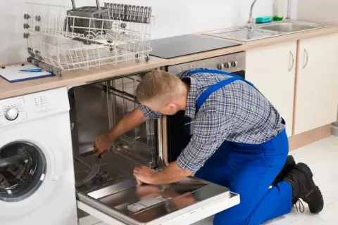 Serwisant naprawia zmywarkę Bosch, która wyświetla błąd E15. Widać też pralkę i kosze na naczynia.