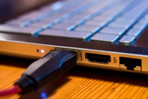 Podłączanie monitora do laptopa przez HDMI. Wtyczka kabla HDMI w porcie laptopa.