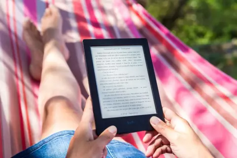 Osoba relaksuje się w hamaku, czytając e-booka. Idealny sposób na relaks, gdy szukasz najlepszego czytnik ebook ranking.