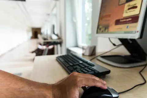 Dłoń na myszce, klawiatura i monitor. Czas dowiedzieć się, jak zaktualizować sterowniki, by komputer działał sprawniej.