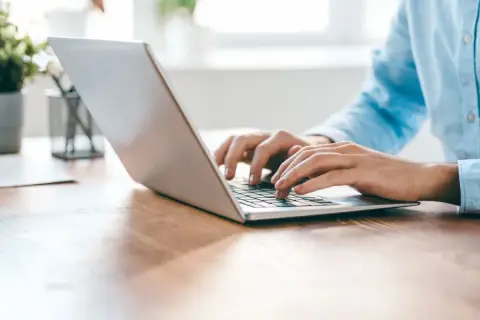 Osoba pisze na laptopie, korzystając z przeglądarki Opera GX z wbudowanym VPN.