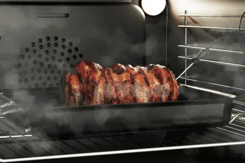 Soczysta pieczeń w piekarniku, wykorzystująca funkcję grill, paruje i apetycznie się rumieni.