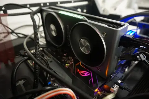 Karta graficzna RTX 2060 z zielonym podświetleniem "GeForce RTX" i wentylatorami. Widać jej dużą ilość vram, podłączoną do płyty głównej z podświetlanym logo ROG.
