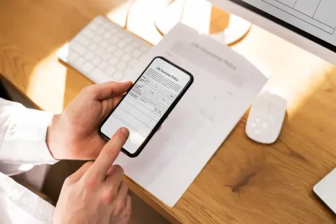 Ręce trzymają telefon, który działa jak skaner w telefonie, skanując dokument "Life Insurance Policy".