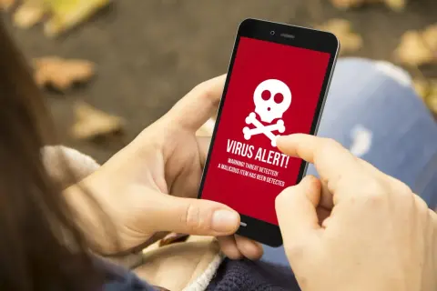 Osoba wykonuje skanowanie telefonu, gdy na ekranie pojawia się czerwony komunikat "VIRUS ALERT!".