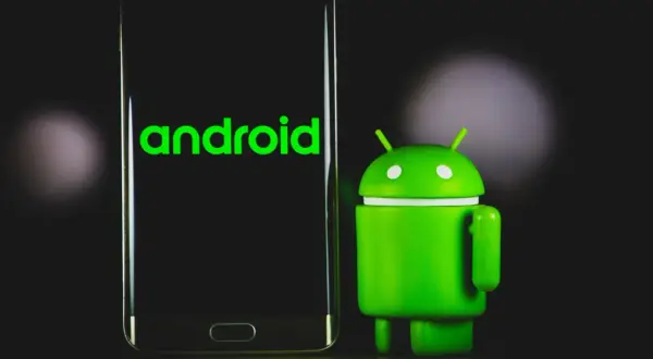 Zielony robot Android obok telefonu z napisem "android 13" na ekranie.