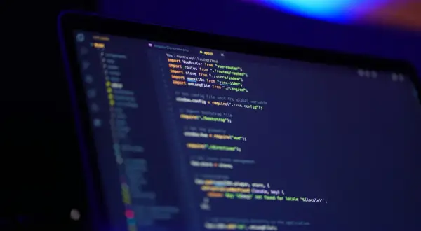 Kod JavaScript na ekranie laptopa, widać fragmenty kodu, importy i komentarze. Oop!
