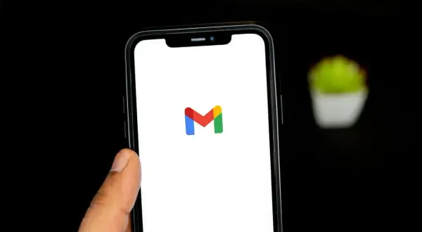 Dłoń trzyma smartfon z logo Gmail. Chcesz wiedzieć, jak wylogować się z Gmail? Ten obrazek pokazuje ekran startowy aplikacji.
