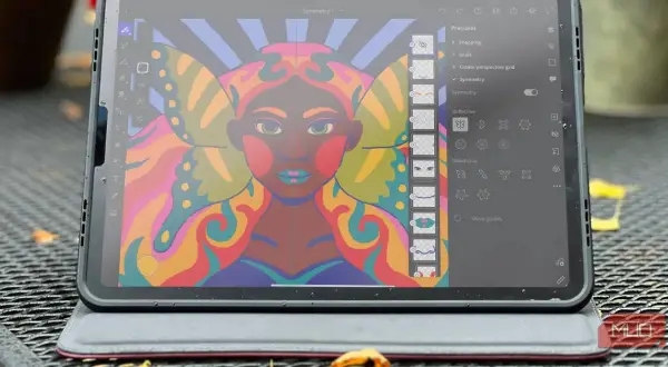 Kolorowy portret kobiety z motylimi skrzydłami, tworzony w aplikacji Adobe Fresco na tablecie. Widoczne narzędzia symetrii.