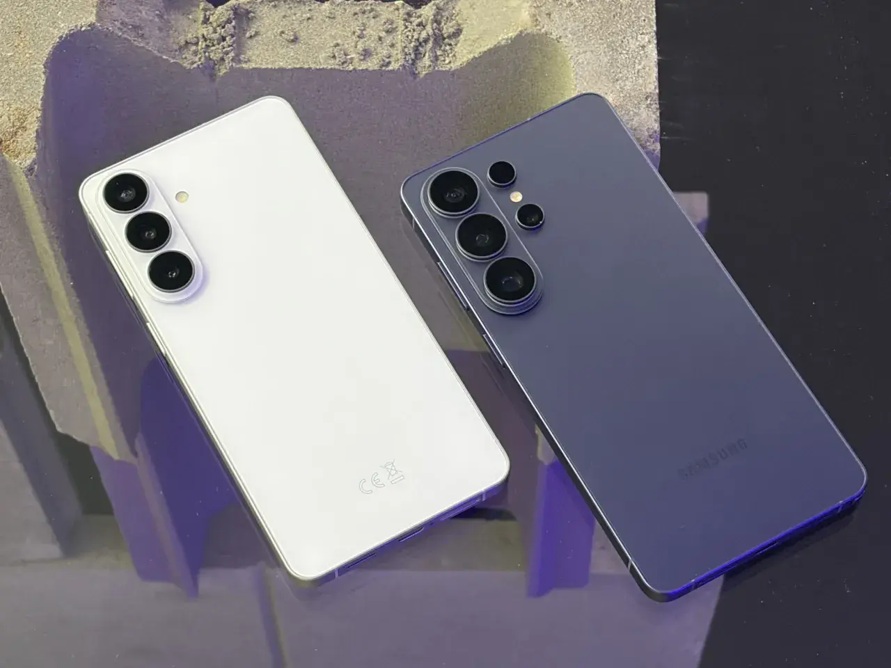 Dwa smartfony Samsung, biały i granatowy, leżą obok siebie. Biały ma trzy aparaty, granatowy cztery. Bixby z pewnością doceniłby ich design.