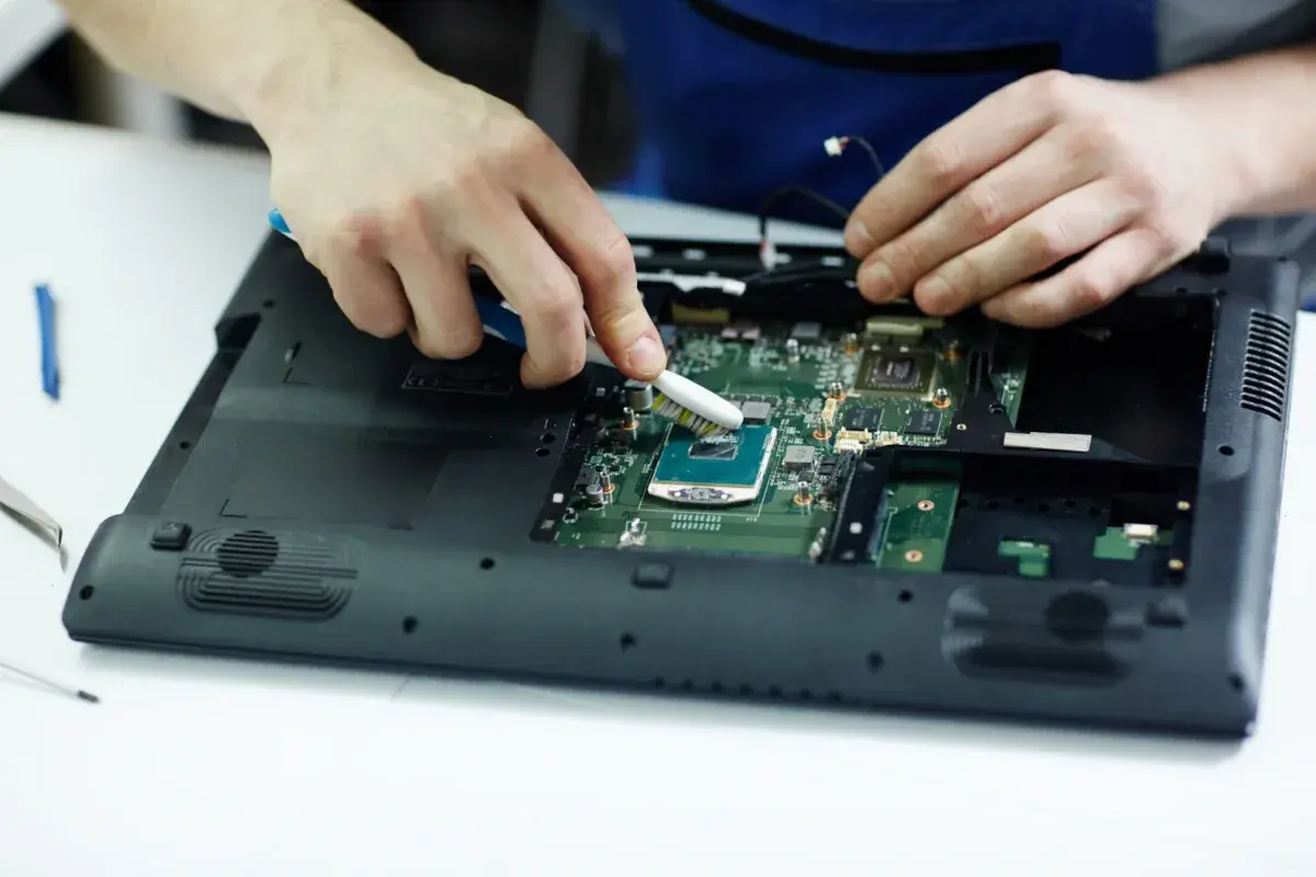 Ręce czyszczą procesor laptopa szczoteczką. Może to pomoże, gdy laptop nie chce się włączyć.