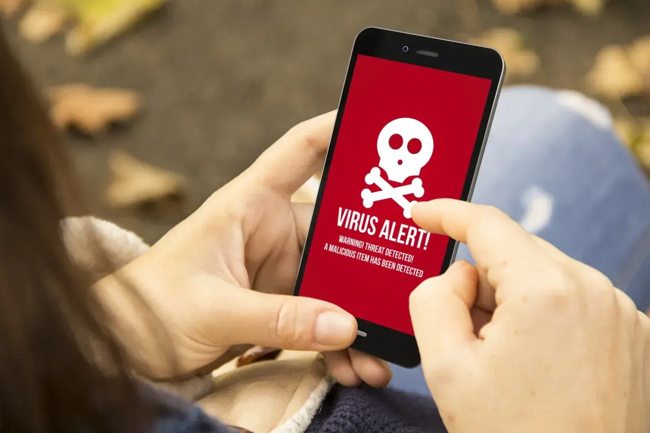 Osoba wykonuje skanowanie telefonu, gdy na ekranie pojawia się czerwony komunikat "VIRUS ALERT!".
