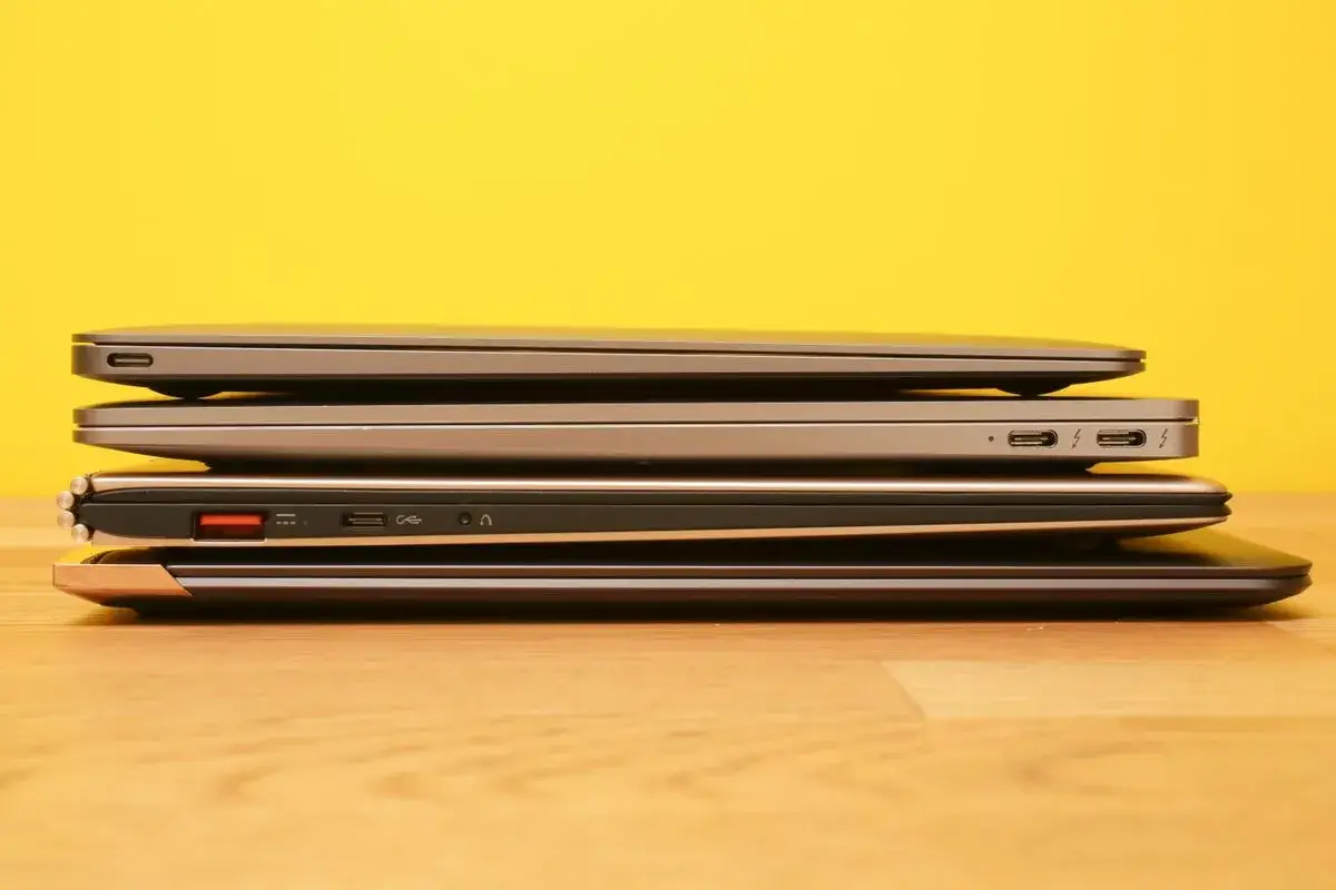 Stos pięciu laptopów, każdy z cienkim bezelem, na drewnianym blacie.