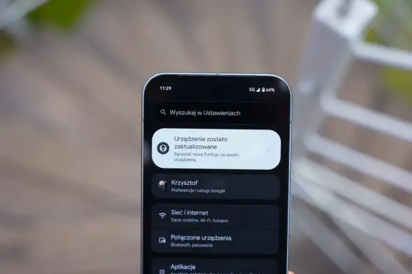 Ekran telefonu z powiadomieniem o aktualizacji systemu. Widoczna jest godzina 11:29, ikona 5G, poziom baterii 64% i menu ustawień, w tym opcje "Sieć i internet" oraz "Połączone urządzenia", typowe dla systemu Android 16.