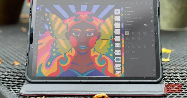 Kolorowy portret kobiety z motylimi skrzydłami, tworzony w aplikacji Adobe Fresco na tablecie. Widoczne narzędzia symetrii.