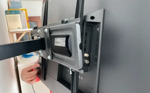 Montaż uchwytu do telewizora, podłączanie urządzeń peryferyjnych. Widoczne złącza HDMI, antenowe i optyczne.